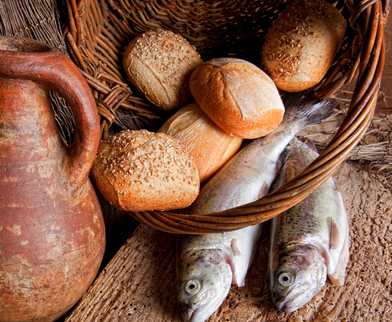 Wine, loaves of bread and fresh fish in an old basket
